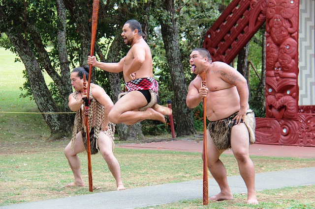 three maori men performing a war dance