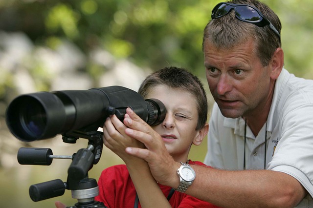 father and son, looking down a high-tech telescope